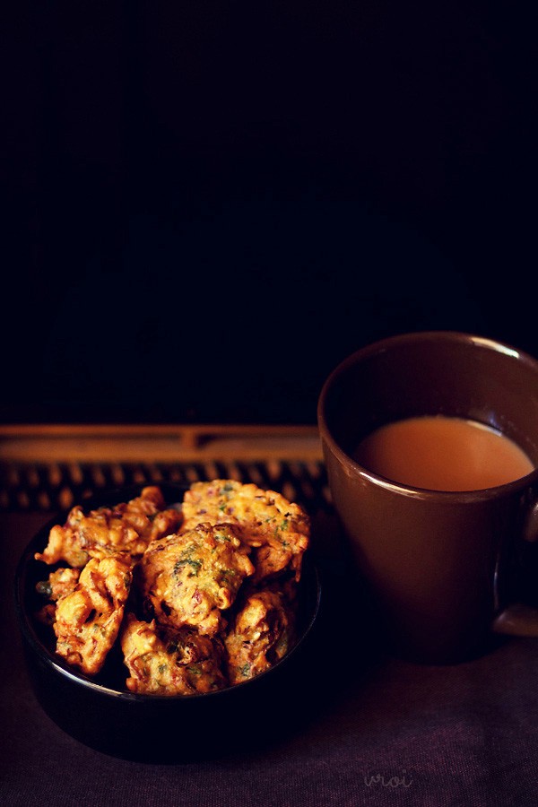 cabbage pakoda served on a black bowl with tea