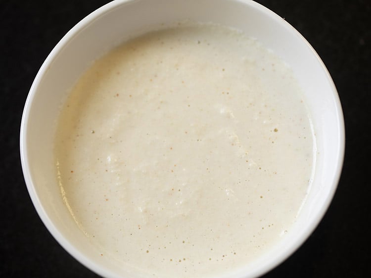 base of coconut chutney in a white bowl on a black background