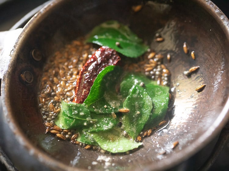 hojas de curry, asafétida y pimiento rojo seco añadidos a la sartén tadka