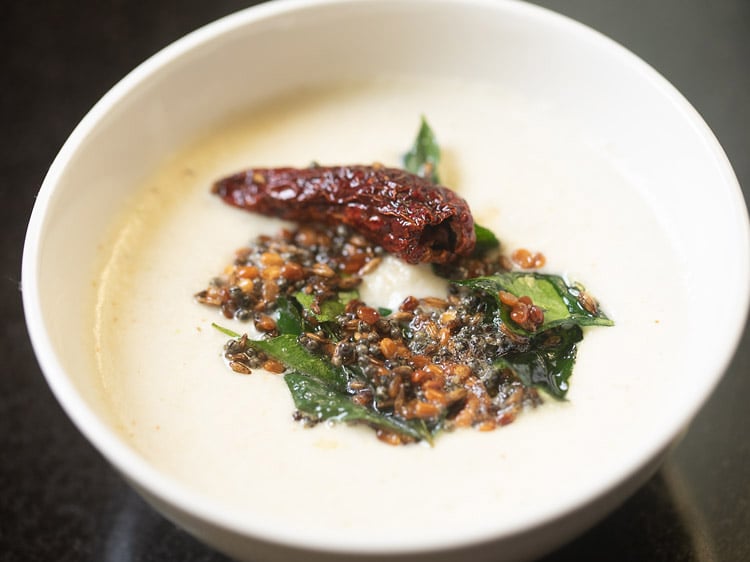 tempered spices and oil poured into white bowl with coconut chutney base