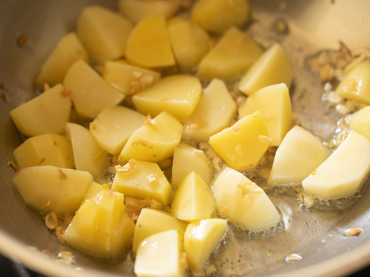 Mixing the potatoes with the garlic and oil mixture.