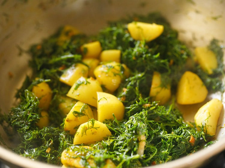 mixing salt with dill leaves in the pan