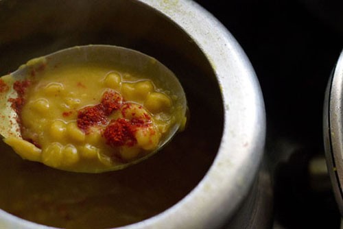 adding red chili powder to the ragda