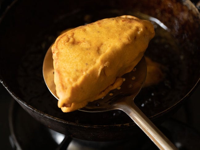 fried bread pakora on a slotted spoon 