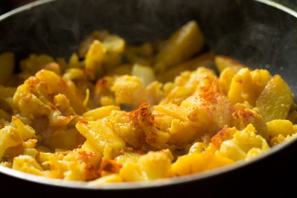 adding garam masala powder to cooked aloo gobi