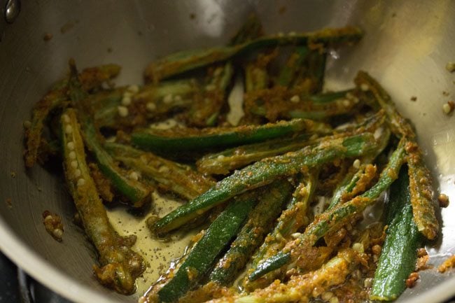 frying marinated sliced bhindi in hot oil to make bhindi fry.