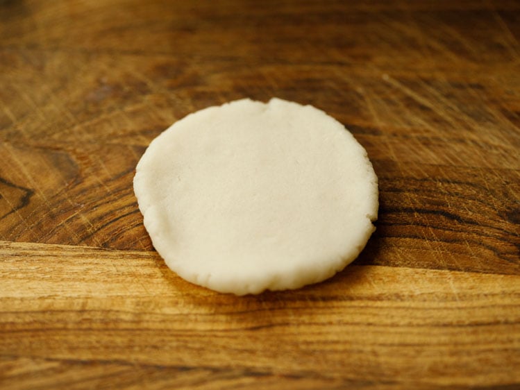 flattened dough ball on a wooden board