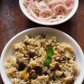 mushroom pulao served on a white plate with a side of sliced onions on a small white plate