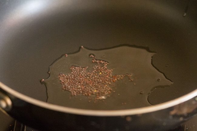 mustard seeds added to hot coconut oil in a pan.