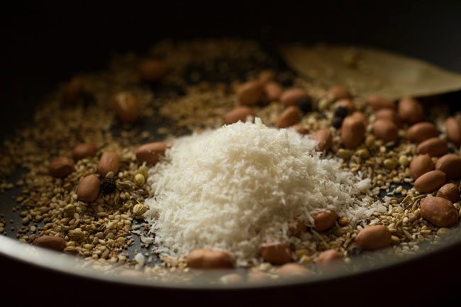 desiccated coconut added to pan with toasted spices.