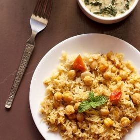 chana pulao served in a white plate with spinach raita