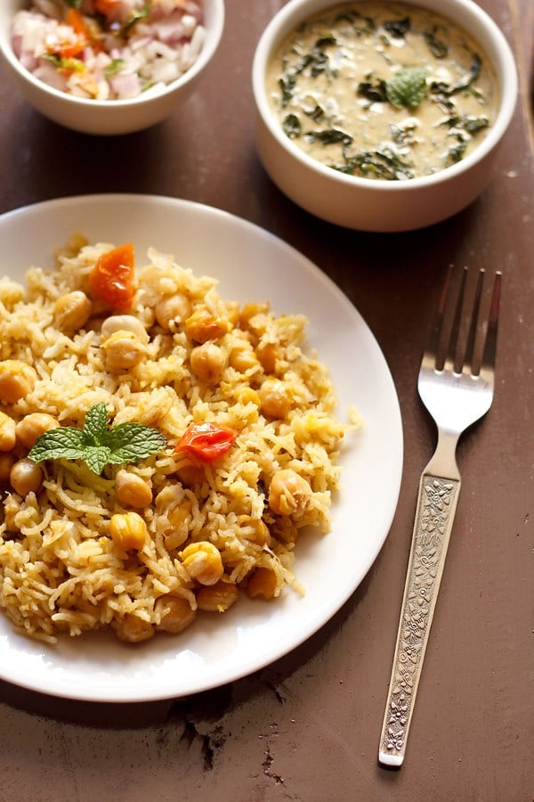 chana pulao served in a white plate with spinach raita