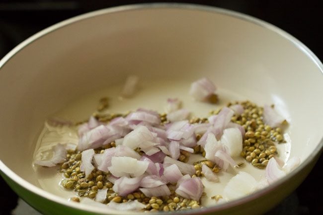 chopped onions, coriander and fennel seeds in a pan