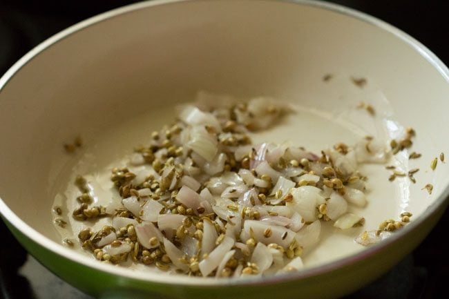 translucent onions, coriander and fennel seeds in a pan