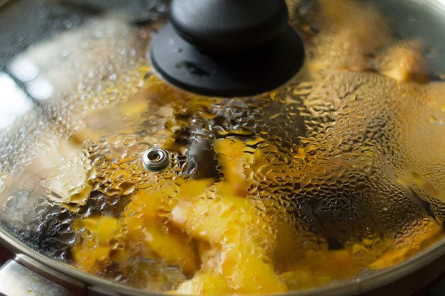 cooking aloo baingan with lid placed on pan