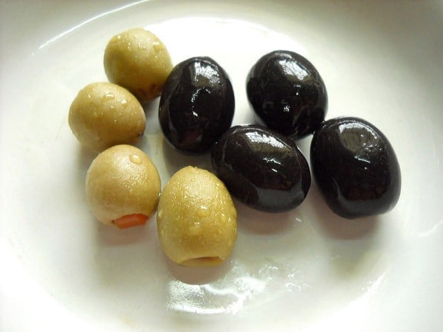 green and black olives on a plate. 