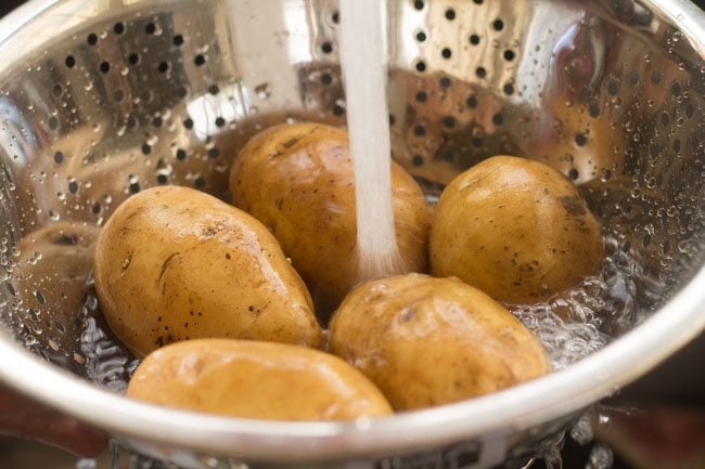 potatoes being rinsed in fresh water in a colander