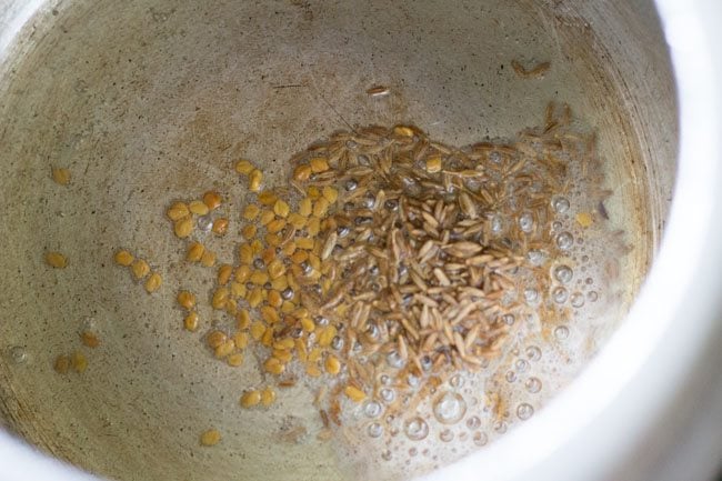 cumin seeds and fenugreek seeds in a pressure cooker