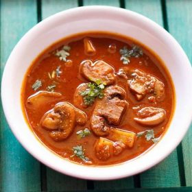 vindaloo recipe with mushrooms garnished with chopped coriander leaves and served in a white bowl.