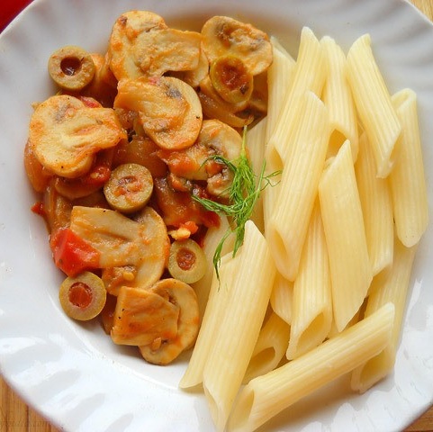 cooked penne pasta and tomato mushroom sauce in a white plate.