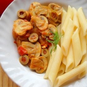 cooked penne pasta and tomato mushroom sauce in a white plate.