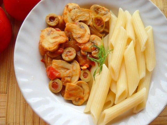 cooked penne pasta and tomato mushroom sauce in a white plate.