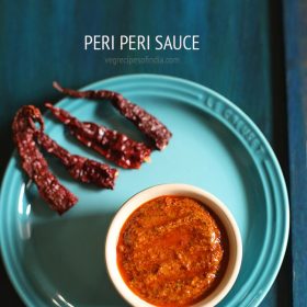 peri peri sauce in a bowl on a blue plate with text layovers.