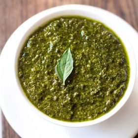 pesto in a white bowl with a small basil leaf on top.