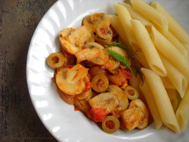 cooked penne pasta and tomato mushroom sauce in a white plate.