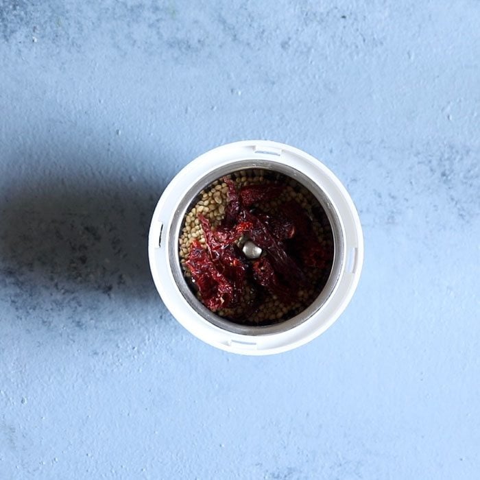 coriander seeds and kashmiri red chilies in a grinder for kadai masala recipe