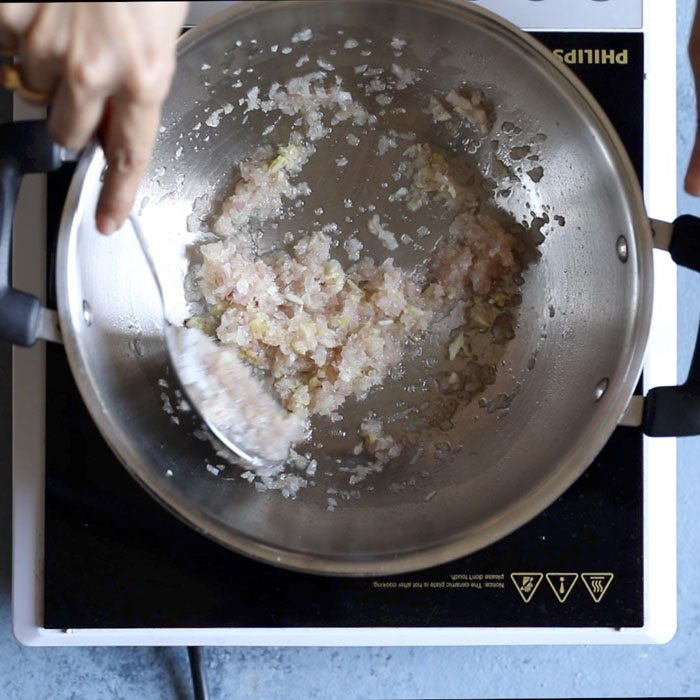 ginger garlic paste being sautéed with a spoon 