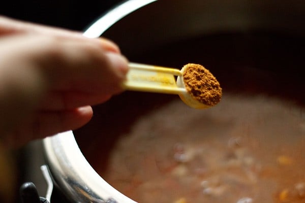 adding garam masala powder to rajma curry in cooker