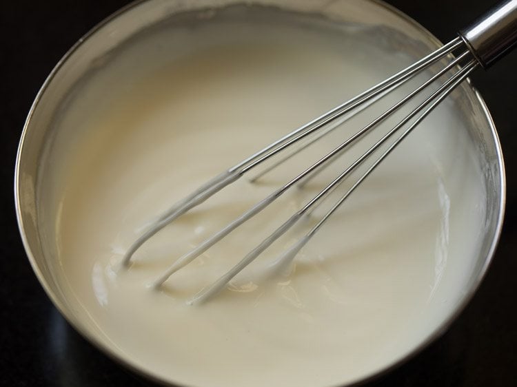 fresh curd being whisked in a bowl