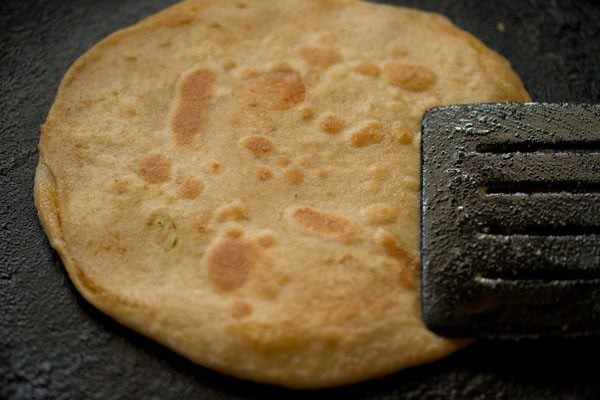 pressing gobi paratha with a spatula