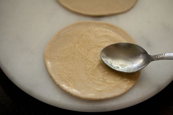 applying ghee on rolled paratha