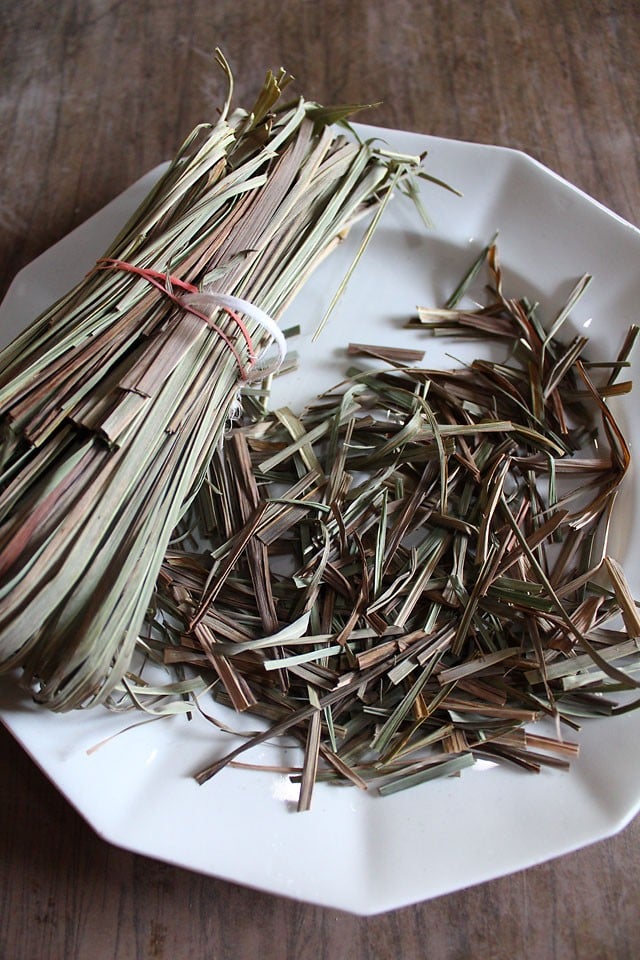 dried lemongrass on a plate with some of it cut into smaller pieces for grinding.