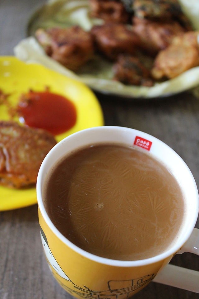 yellow printed mug filled with masala chai that has been flavored with milk and sugar.