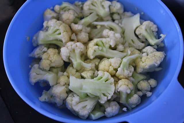 cauliflower florets in a blue colander after blanching.