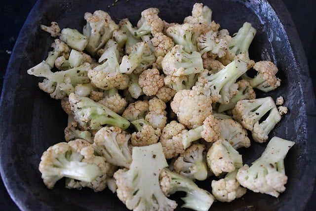 blanched cauliflower florets tossed in herb oil mixture for baked cauliflower recipe.