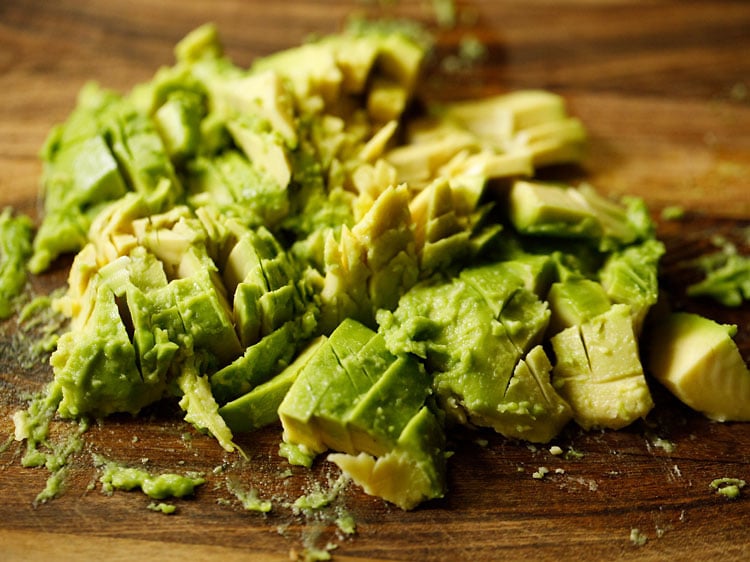 chopped avocado on a wooden chopping board.