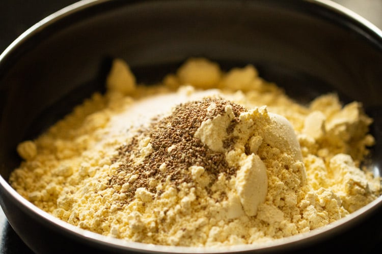 cornmeal and carom seeds in a black mixing bowl