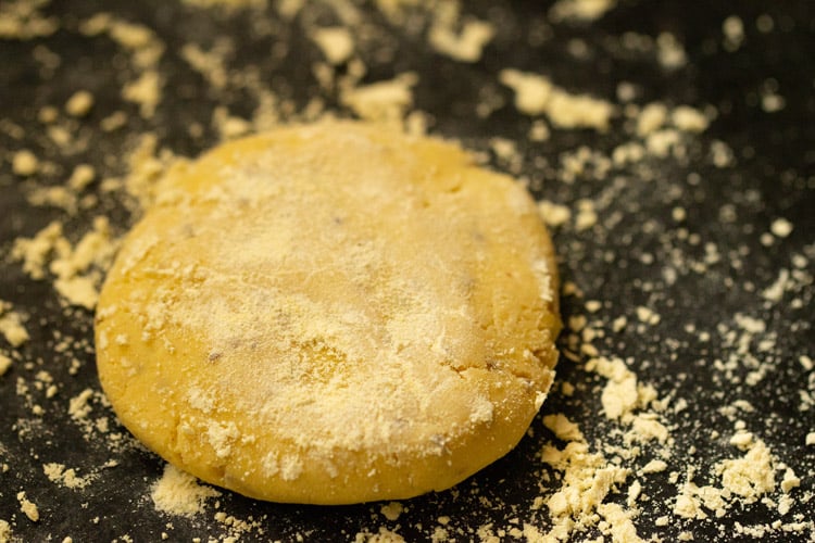 maize flour sprinkled on flattened dough on a black work surface