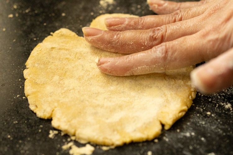 flattening dough with fingers to make makki ki roti
