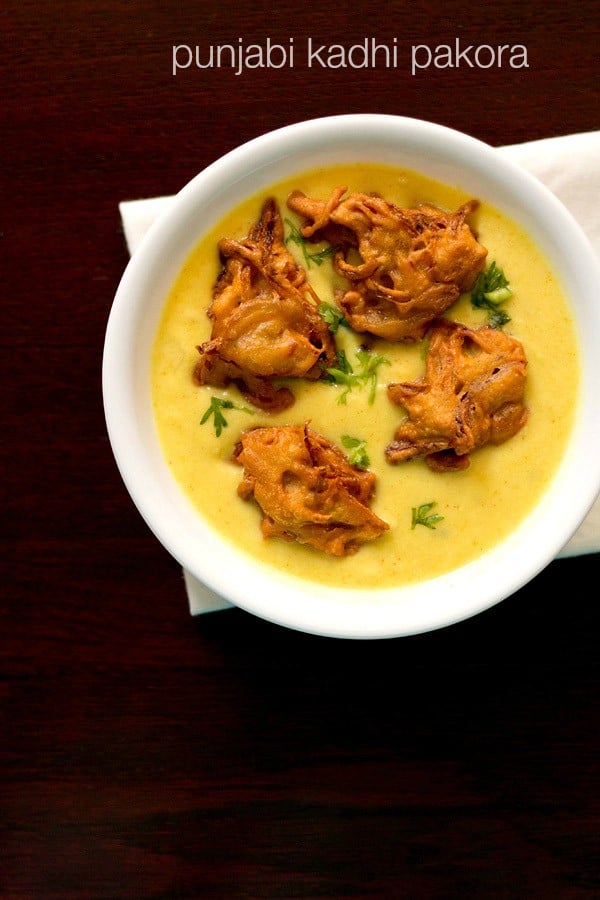 punjabi kadhi pakora garnished with coriander leaves served in a white bowl.