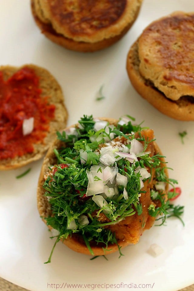 potato filling bun half topped with chopped onion and coriander leaves. 