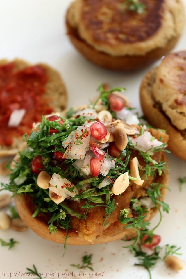 potato filling bun half topped with roasted peanuts, fresh pomegranate pearls and dabeli masala. 