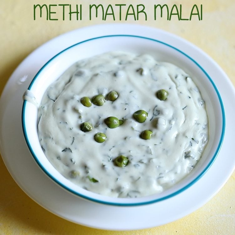 methi matar malai in a white bowl with a light blue rim, garnished with a few peas and a sprig of fresh coriander.