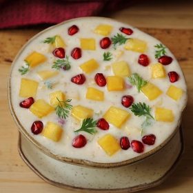 pineapple raita garnished with coriander and pomegranate arils in a ceramic bowl