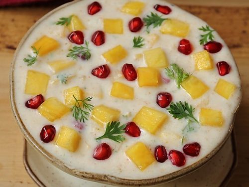 pineapple raita garnished with coriander and pomegranate arils in a ceramic bowl