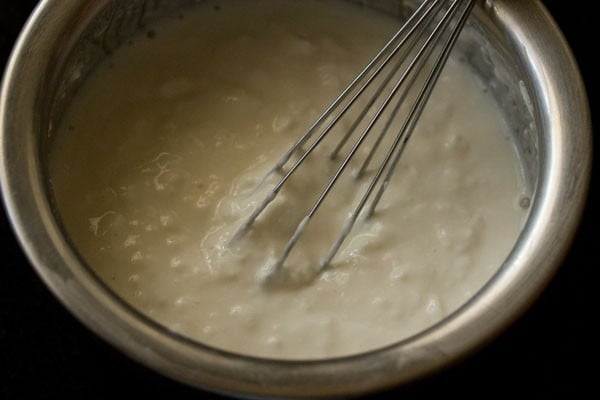 whipping curd with a whisk for making pineapple raita.